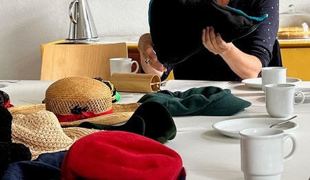 Silke Meyer hält einen Hut in der Hand, weitere liegen auf dem Tisch